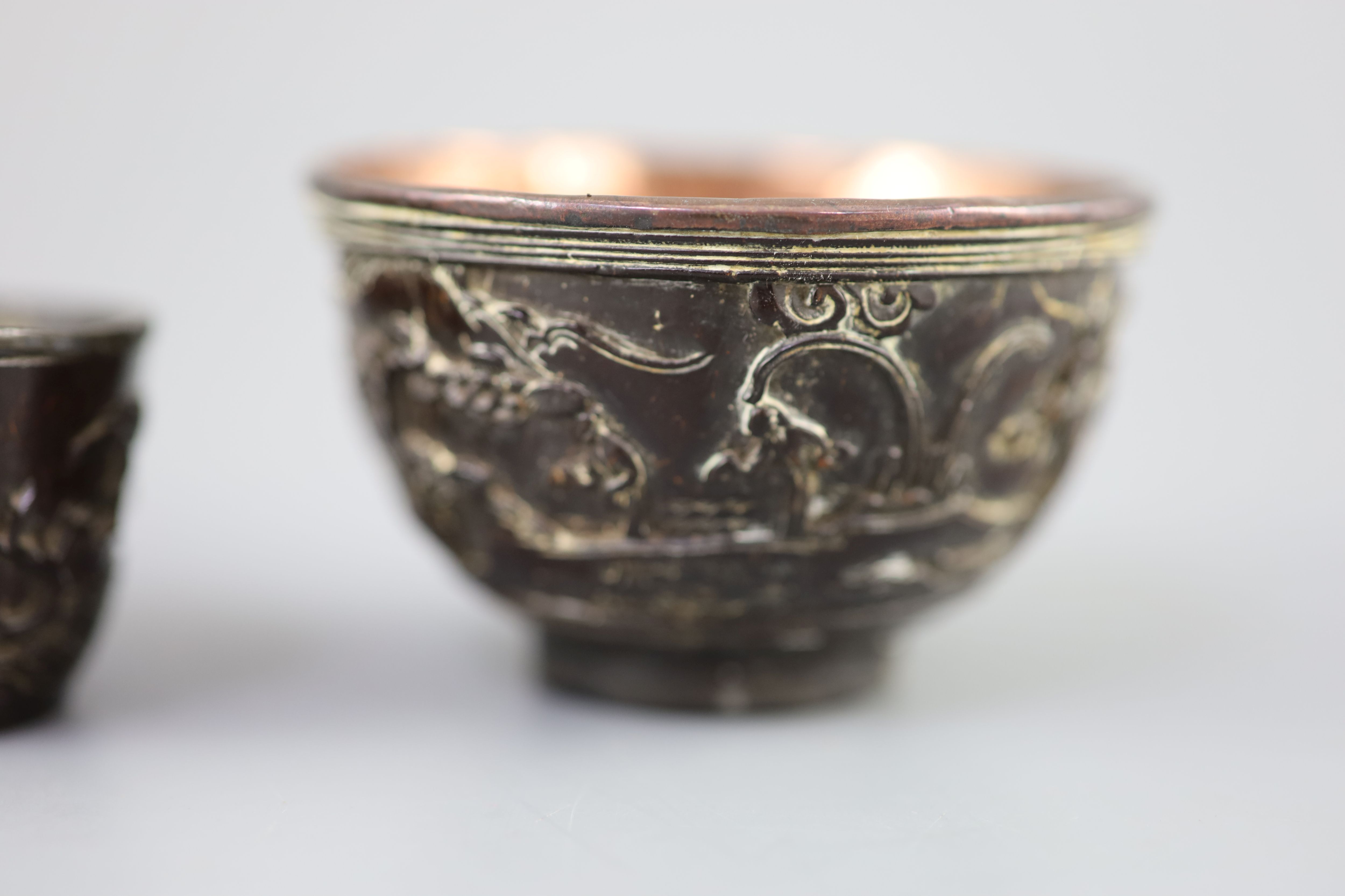 A pair of Chinese coconut landscape cups and a similar peach-shaped cup, 18th/19th century,